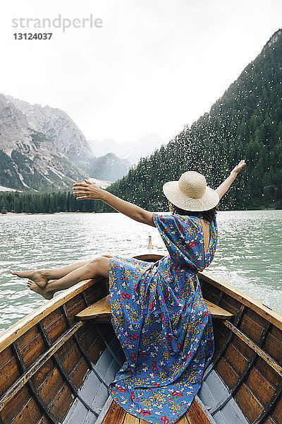 Glückliche Frau genießt Ruderbootfahren über See gegen Berge