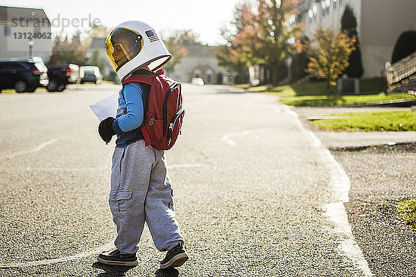 Junge mit Weltraumhelm geht in der Stadt auf der Straße