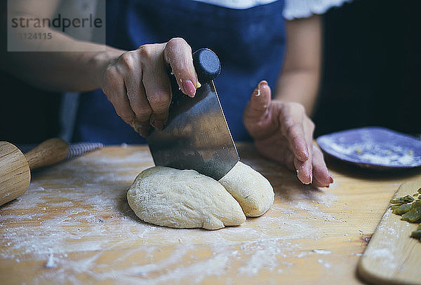 Mitschnitt einer Frau  die an der Küchentheke Brotteig schneidet