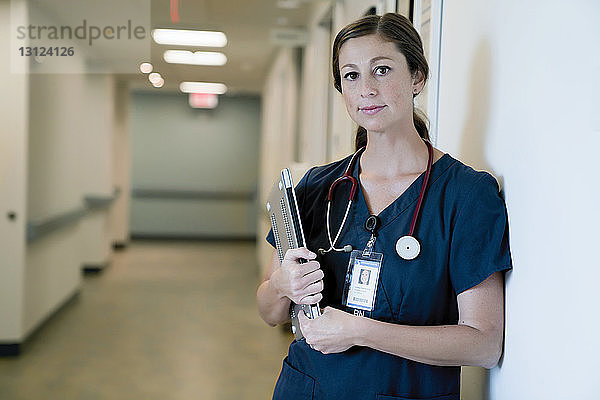 Porträt einer selbstbewussten Ärztin  die einen Laptop-Computer hält  während sie in der Krankenhauslobby steht