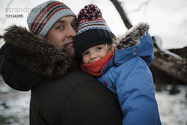 Porträt eines Vaters  der seine Tochter trägt  während er im Winter im Freien steht