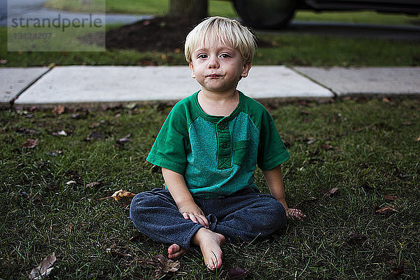 Porträt eines weinenden Jungen  der im Hinterhof sitzt