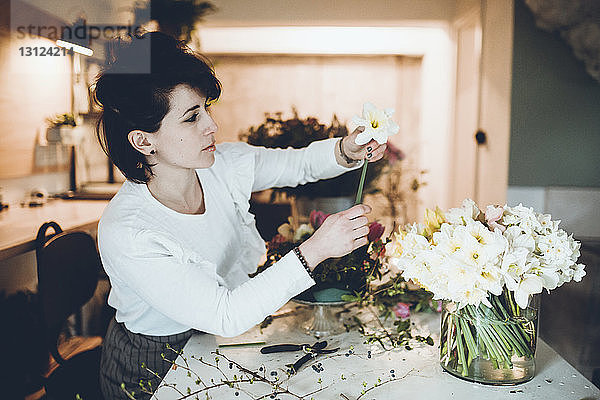 Seitenansicht eines Floristen  der Narzissen in einer Vase im Blumenladen arrangiert