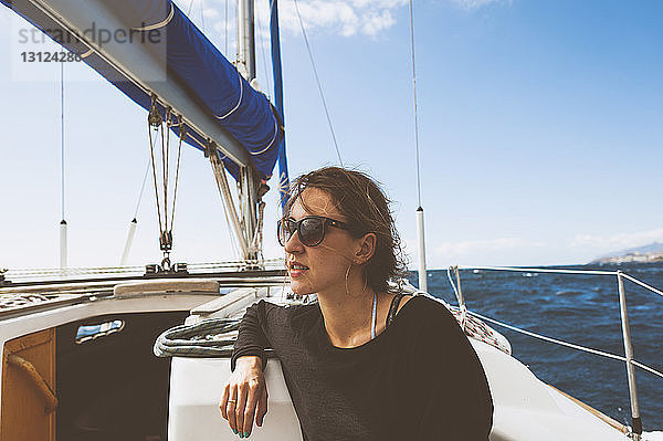 Junge Frau reist in einem Segelboot auf See gegen den Himmel