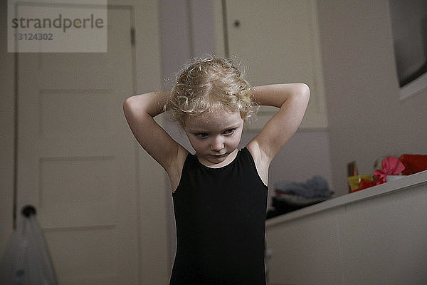 Mädchen bindet die Haare im Stehen zu Hause