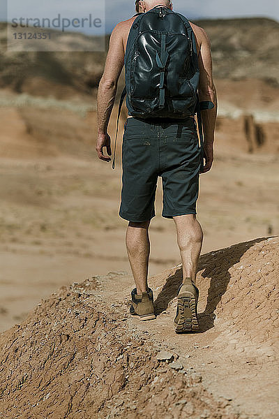Rückansicht eines Wanderers mit Rucksack  der bei Sonnenschein die Wüste erkundet