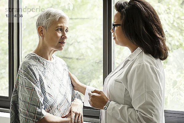 Arzt bespricht sich mit Patient  während er im Krankenhaus am Fenster steht