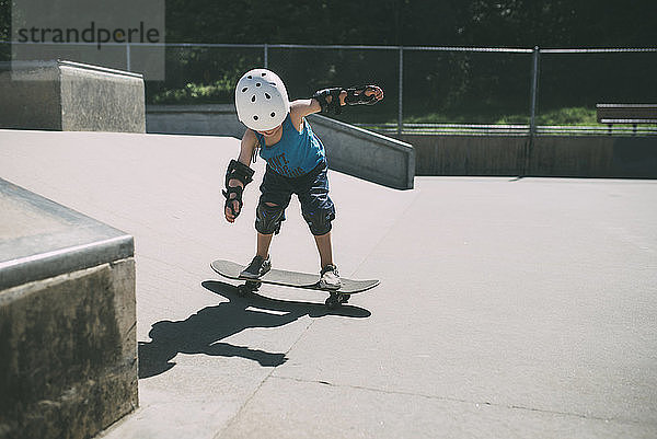 Skateboarden von Jungen in voller Länge im Sommer im Skateboard-Park