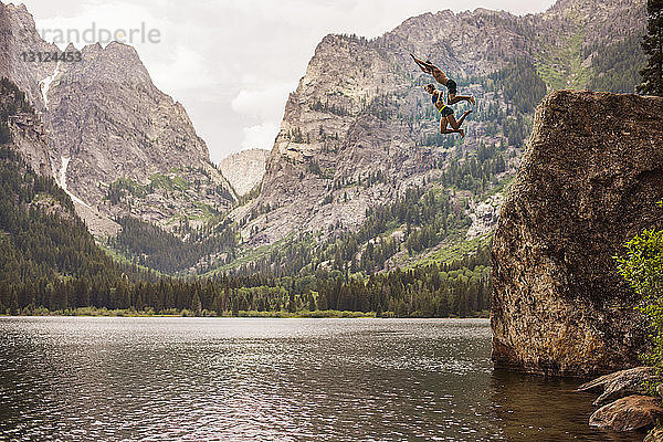 Freunde tauchen von einer Klippe im Grand-Teton-Nationalpark in den See