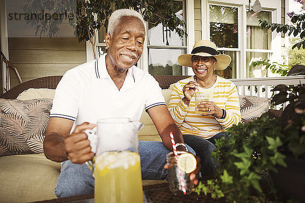 Glückliches älteres Ehepaar trinkt Limonade  während es auf der Veranda sitzt