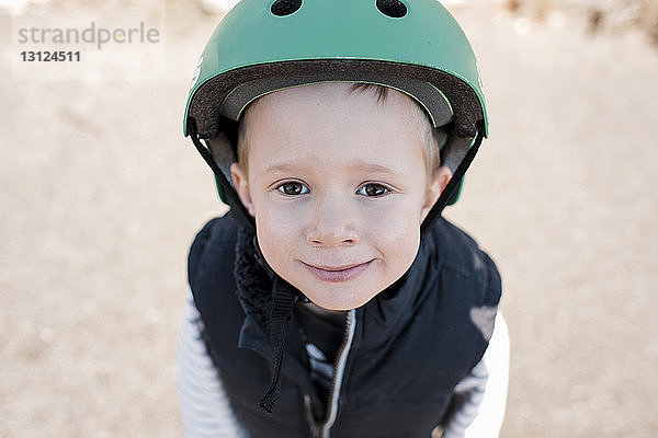 Hochwinkelporträt eines Jungen mit Helm  der im Park steht