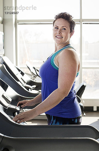 Porträt einer Frau  die auf dem Laufband im Fitnessstudio trainiert