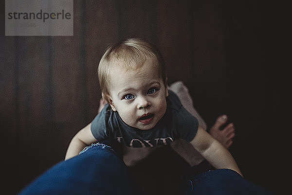 Portrait einer niedlichen Tochter  die die Beine der Mutter hält  während sie zu Hause auf dem Boden steht