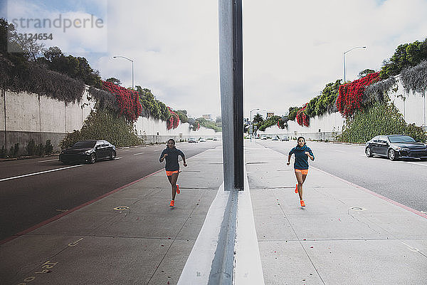 Sportlerin rennt auf Gehweg durch Glasgebäude