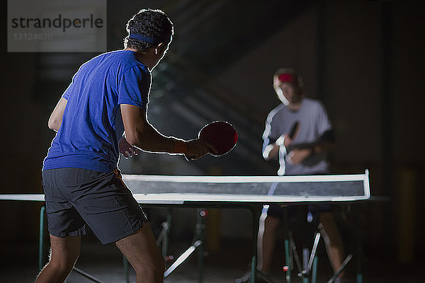Freunde spielen Tischtennis gegen beleuchtetes Gebäude