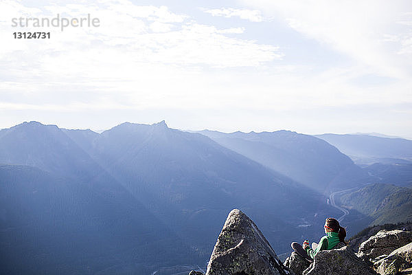 Hochwinkelaufnahme einer Frau  die sich auf Felsen gegen eine Bergkette entspannt