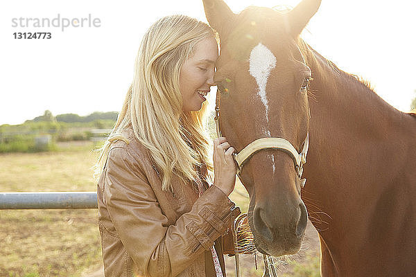 Glückliche Frau streichelt Pferd auf dem Bauernhof