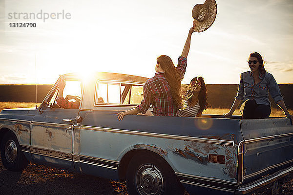 Freunde genießen im Pick-up bei Sonnenuntergang