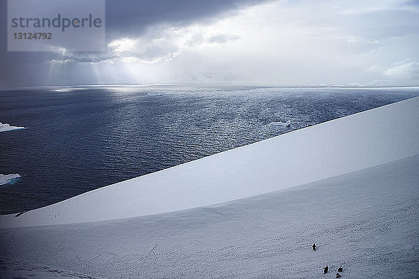 Szenische Ansicht des Meeres durch ein schneebedecktes Feld gegen den Himmel