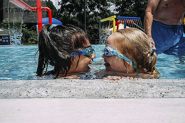 Glückliche Freunde im Schwimmbad des Ferienorts