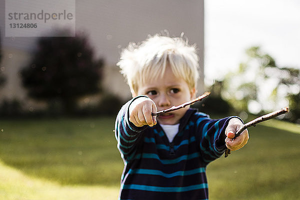 Junge spielt mit Stöcken im Hinterhof