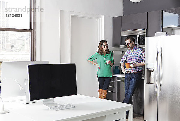 Kreative Geschäftskollegen halten Kaffeetassen in der Hand  während sie im Büro diskutieren