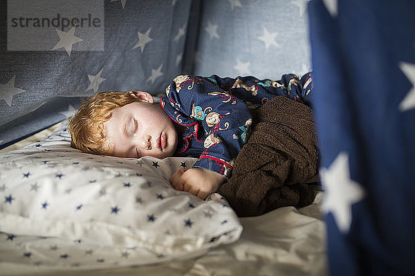 Nahaufnahme eines süßen Jungen  der zu Hause im Zelt auf dem Bett schläft