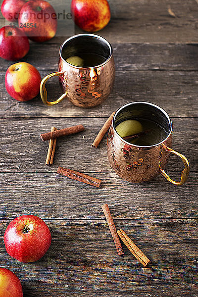 Hochwinkelansicht von Äpfeln und Zimt mit Getränken auf Holztisch