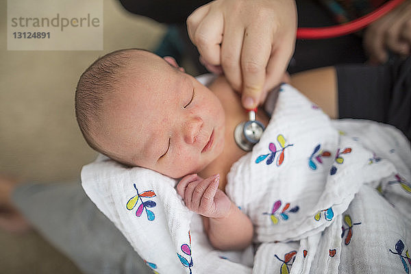 Abgetrennte Hand der Hebamme  die das von der Mutter zu Hause getragene Neugeborene untersucht