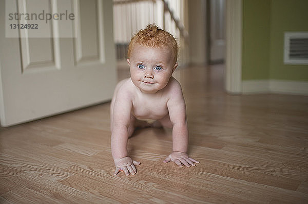 Porträt eines süßen Jungen ohne Hemd  der zu Hause auf dem Boden krabbelt