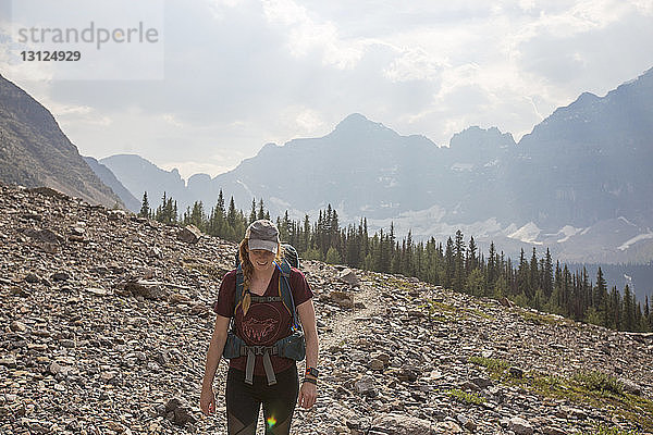 Frau mit Rucksack steht auf Feld im Banff-Nationalpark gegen den Himmel