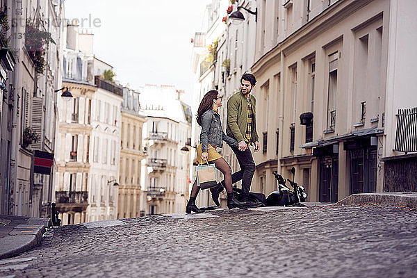 Junges Paar unterhält sich beim Überqueren der Straße in der Stadt