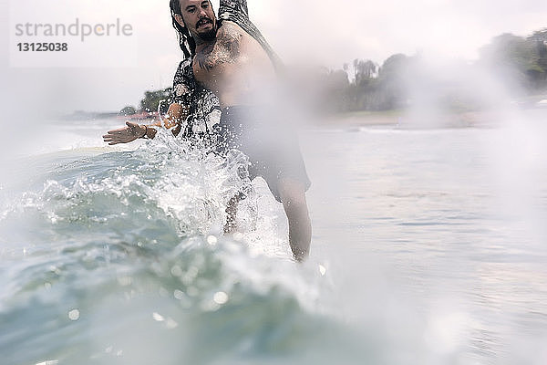 Mann balanciert beim Surfen im Meer