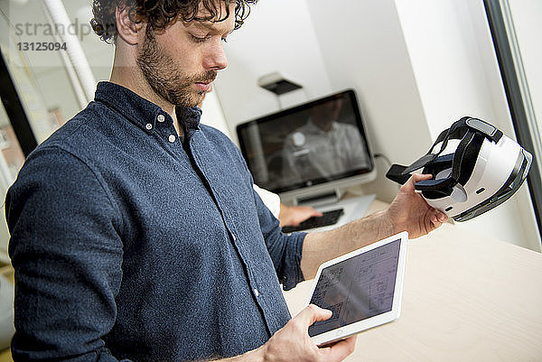 Ingenieur mit Tablet-Computer bei der Untersuchung eines Virtual-Reality-Simulators im Büro