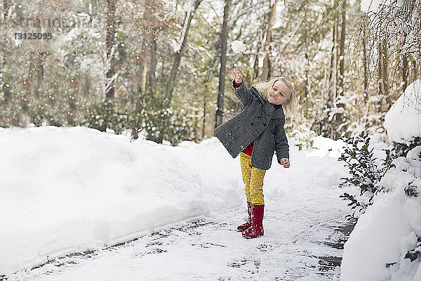 Fröhliches Mädchen spielt auf schneebedecktem Feld im Park