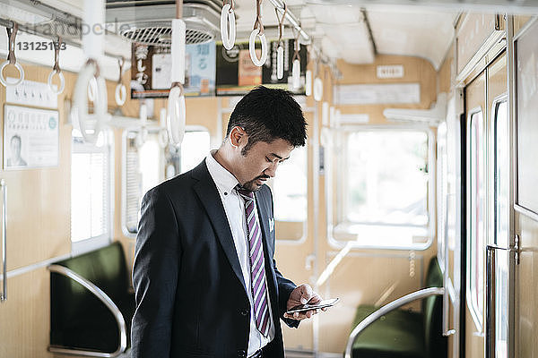 Geschäftsmann benutzt Smartphone im Zug stehend