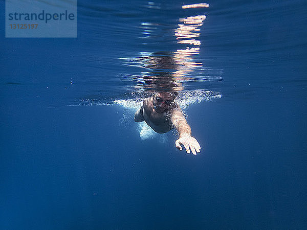 Mann schwimmt im Meer unter Wasser