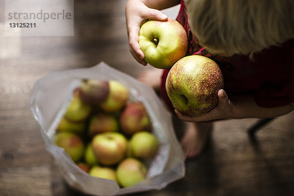 Hochwinkelaufnahme eines Jungen  der zu Hause Äpfel hält