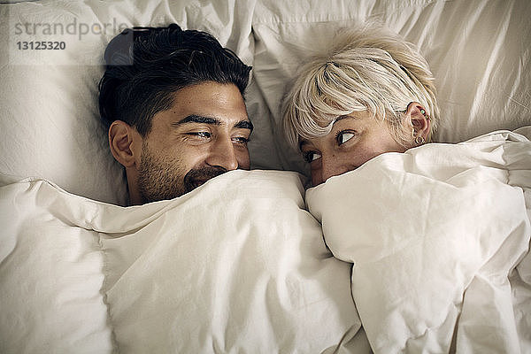 Draufsicht eines glücklichen Paares  das sich im Bett anschaut