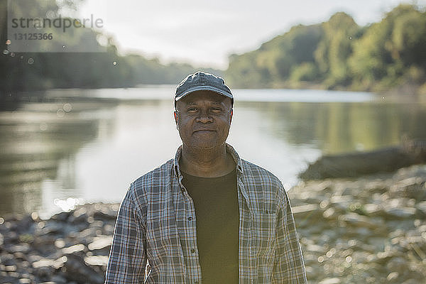 Porträt eines lächelnden Mannes am Seeufer stehend