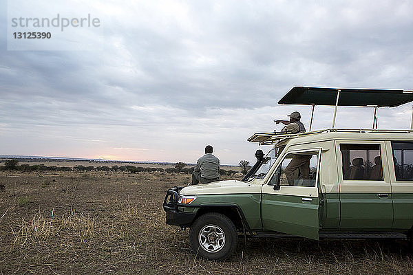 Männliche Freunde im Geländewagen im Serengeti-Nationalpark bei Sonnenuntergang