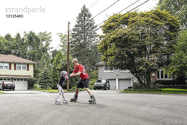Vater bringt Tochter das Inline-Skaten auf der Straße bei