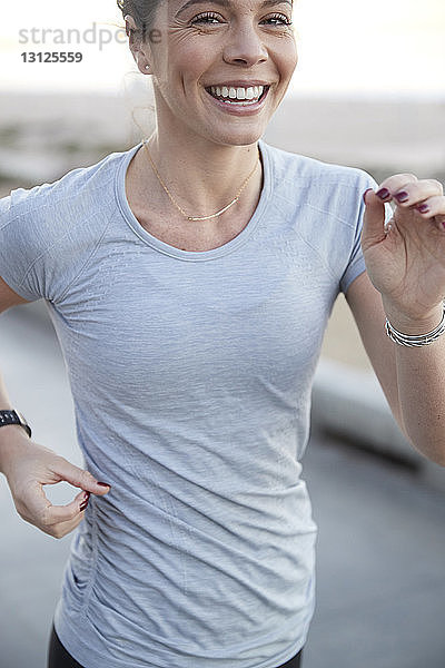 Porträt einer fröhlichen Frau  die auf einem Fußweg joggt