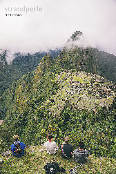 Rückansicht der auf dem Berg sitzenden Freunde gegen Machu Picchu