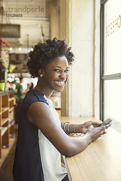 Porträt einer glücklichen Frau  die ein Smartphone in der Hand hält