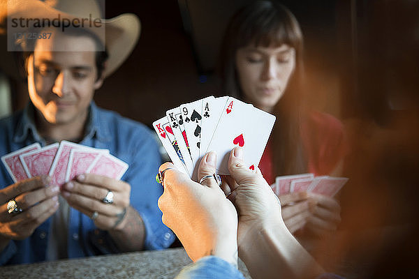 Ausgeschnittenes Bild einer Frau  die Karten hält  während sie mit Freunden im Wohnmobil spielt