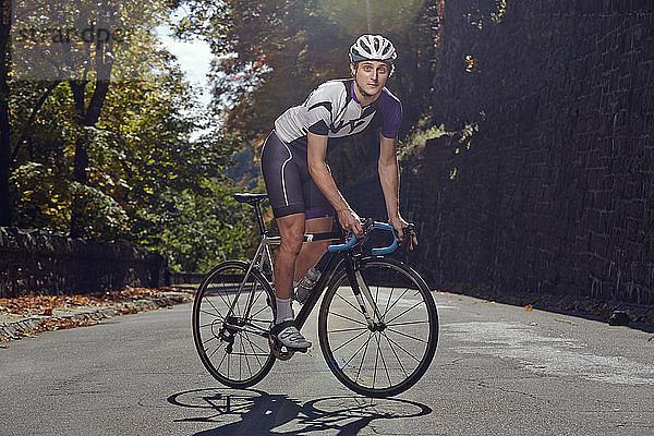 Porträt eines selbstbewussten männlichen Sportlers mit Fahrrad auf der Strasse
