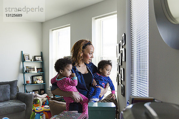 Mutter und Töchter schauen zu Hause durch Fensterläden