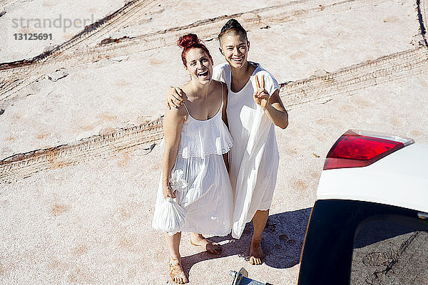Hochwinkel-Portraitaufnahme von glücklichen Freundinnen  die am Strand stehen