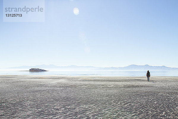 Rückansicht einer Frau  die auf Antelope Island bei klarem Himmel am sonnigen Tag spazieren geht